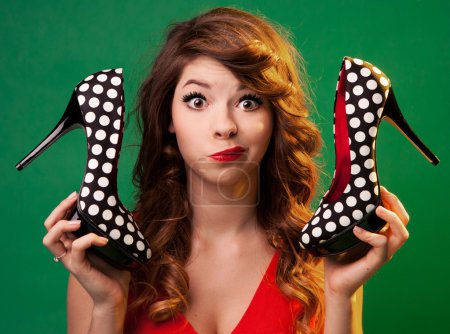 Funny young woman holding high heels shoes