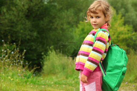 Little girl with backpack outdoor in summer