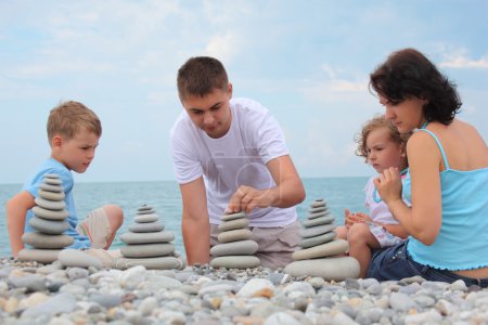 Family builds stone stacks on pebble beach