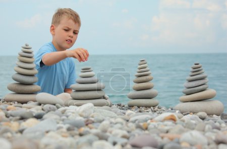 Boy and stone stacks on pebble beach