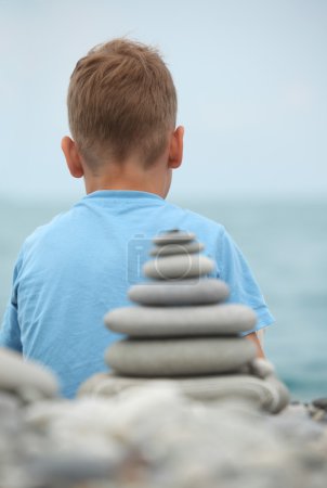 Boy and stone stack, rear view