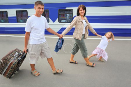 Happy family with little girl going on railway station