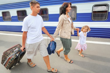 Happy family with little girl going on railway station