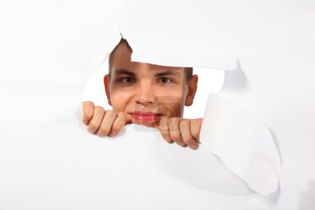 Young man looking out in hole in paper