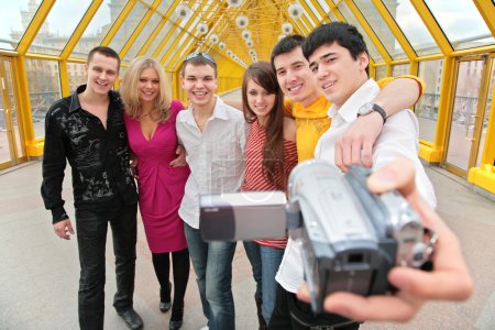 Group of young persons removes itself to video camera on footbridge