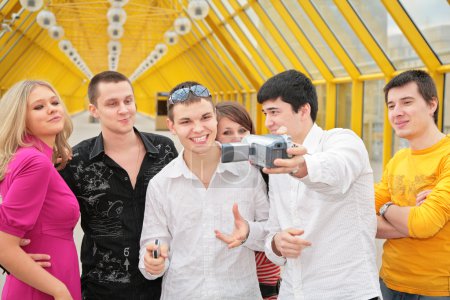 Group of young removes itself to camcorder on footbridge