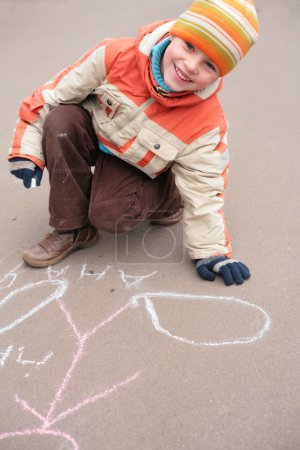 Boy drawing by chalk on asphalt