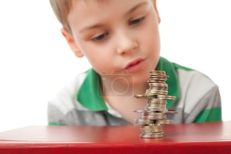 Boy in striped T-shirt looking at curve pile from coins coins