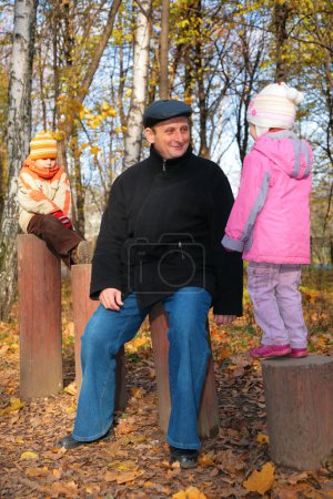 Grand-dad with grandsons in forest in autumn