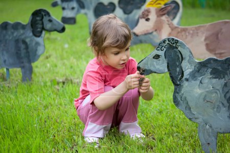 The girl and the boy feed a wooden animals