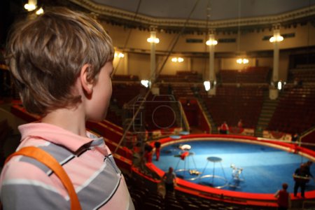 Little boy in circus with blue arena waiting for performance and