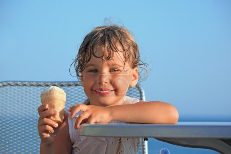 Smiling little girl eats ice-cream on resort