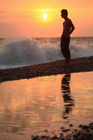 Silhouette guy on sunset wavy beach