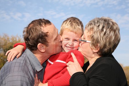 Grandmother and grandfather kiss the grandson