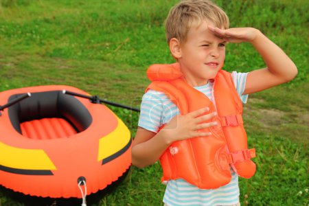 Boy keeps watch and inflatable boat on lawn