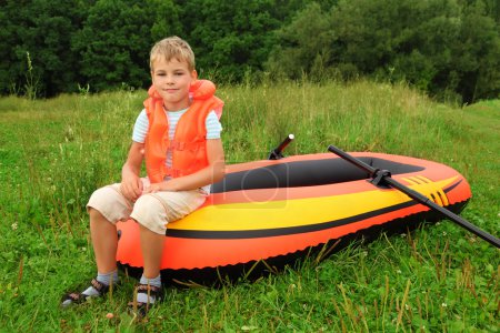Boy sits on an inflatable boat on lawn