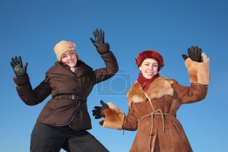 Two young woman posing agains blue sky in winter