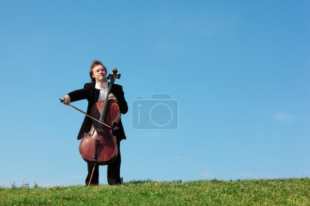 Musician plays violoncello against sky