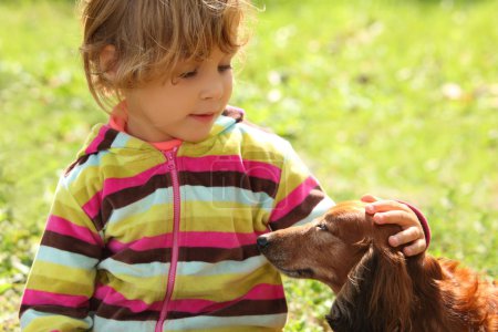 Little girl caress dachshund outdoor
