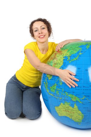 Young beauty woman sitting near big inflatable globe and smiling