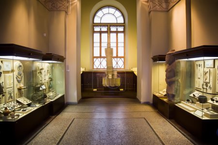 Museum exhibits of ancient relics in glass cases, big window in