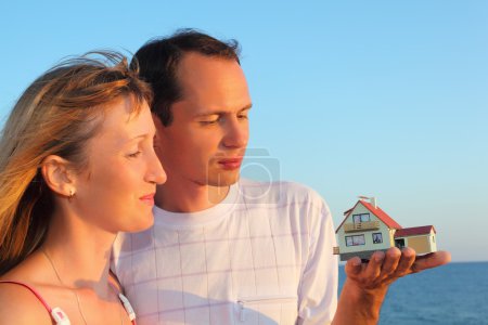 Young woman and man keeping in hands model of house with garage