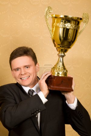Smiling businessman in suit with win cup in hand