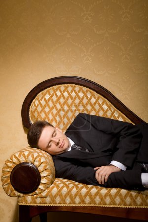 Businessman in suit sleeping on sofa in room