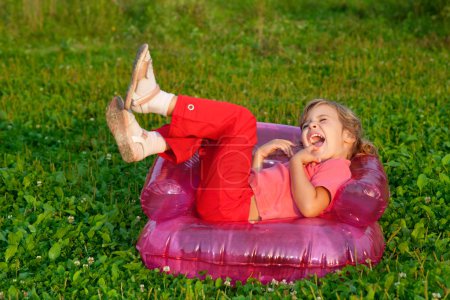 Young girl playing tricks in inflatable armchair outdoors