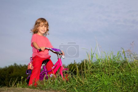Young curly girl biker rests in the field