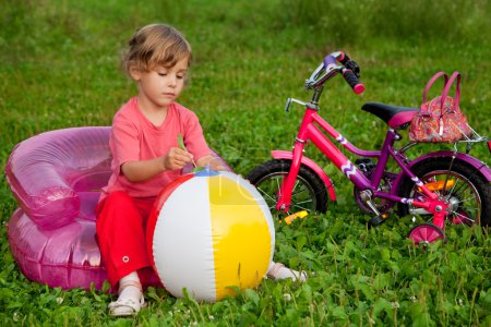 Young girl sits in inflatable armchair in front of bike