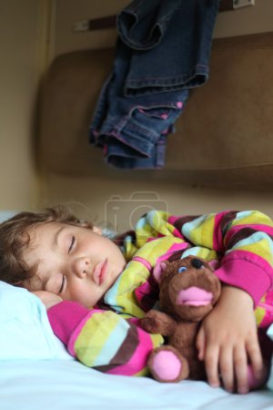 Little girl sleeps in train with puppet