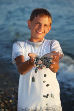 Teenager boy with handful of stones in hands, scatter stones