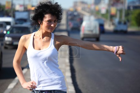 Young woman hitchhiking on highway