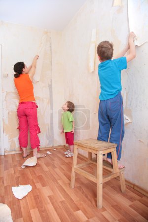 Mother with children break wallpapers from wall