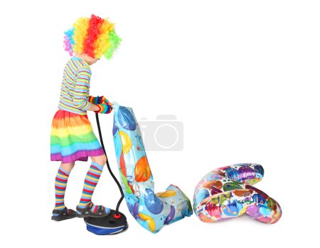 Boy in clown dress pupming birthday balloons isolated on white b