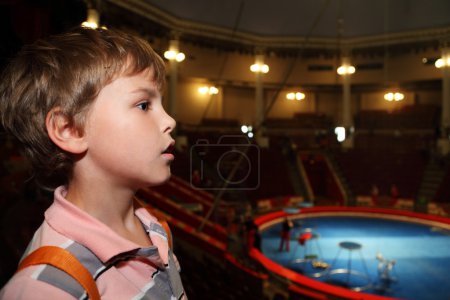 Profile of little boy in circus with blue arena looking at side