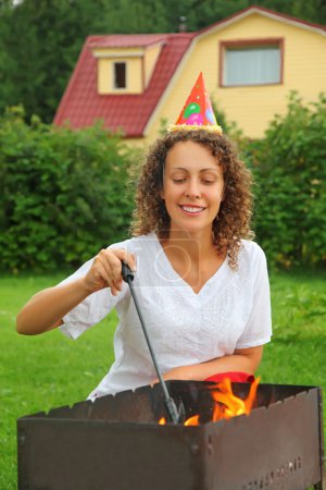Young woman near in cap brazier on picnic, happy birthday