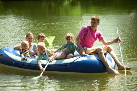 Children and adults float on an inflatable boat and fish a net.