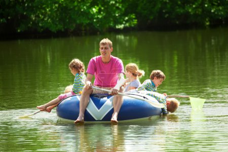 Children and adults float on an inflatable boat in a sunny day