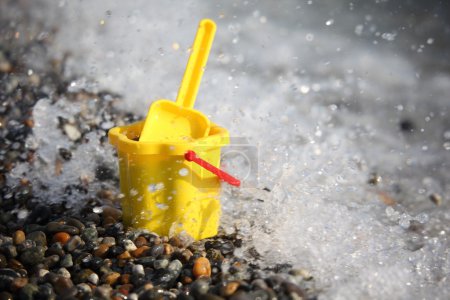 Yellow children's bucket with scoop on seacoast