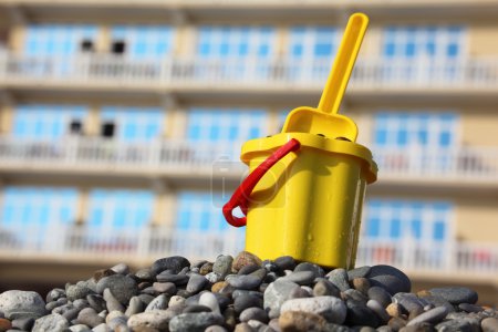 Yellow children's bucket with scoop on pebble