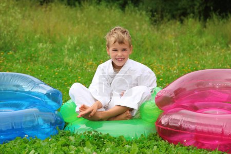 Karate boy sits in inflatable armchair on lawn