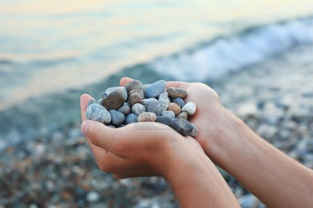 Handful of stones in hands, Against stones and sea