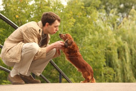 Young man plays with his adorable dachshund outdoor