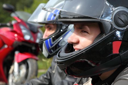 Portrait of two motorcyclists sitting on country road near bike