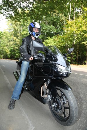 Motorcyclist standing on road
