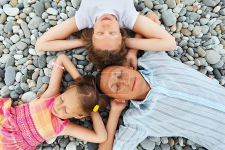 Happy family with little girl lying on stony beach, Concerning w