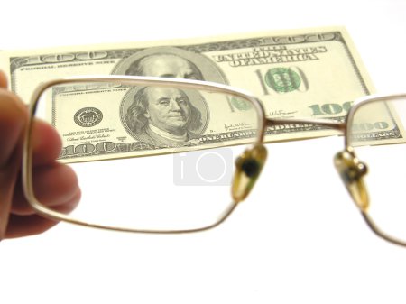 One hundred dollars by the closeup through the eyeglasses on white backgoun