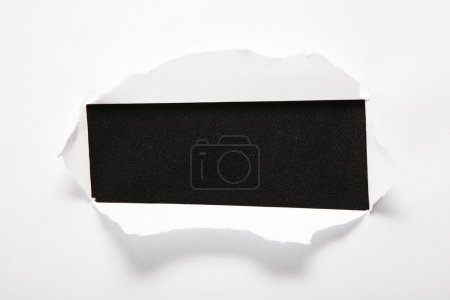 The sheet of paper with the rectangular hole against the black background